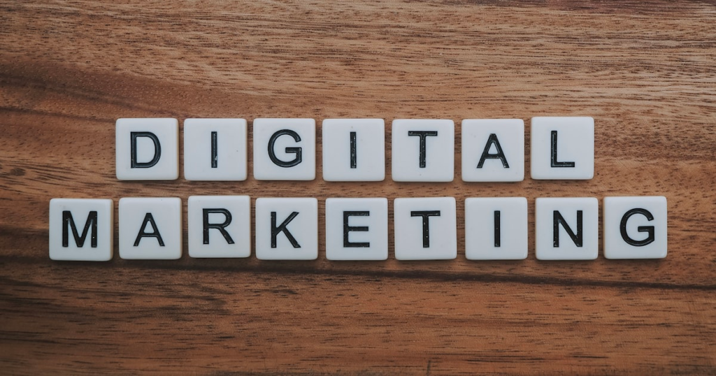 White letter tiles spell out DIGITAL MARKETING on a wooden surface, arranged in two horizontal rows—perfectly capturing the focus of a full service marketing agency that delivers everything from content marketing packages to website maintenance.