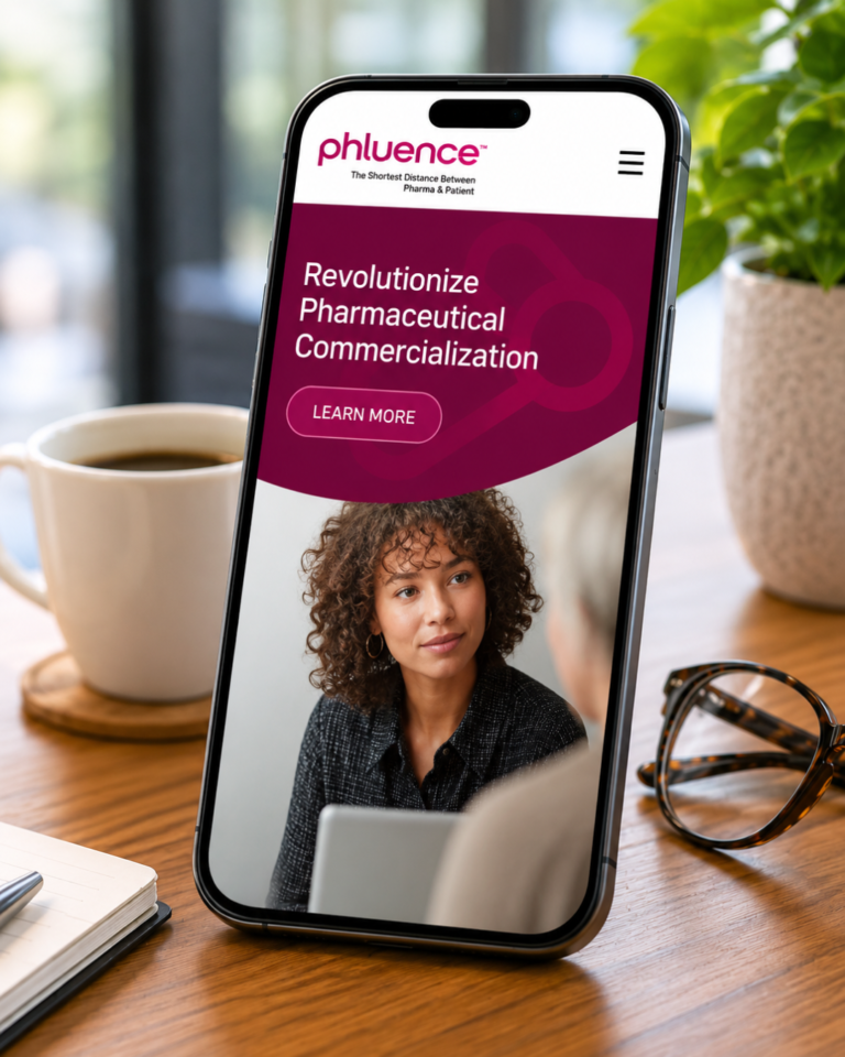 A smartphone on a desk displays a website about pharmaceutical commercialization by a digital marketing agency, with a woman’s photo on the screen. Nearby are a cup of coffee, a notebook, pen, and glasses.